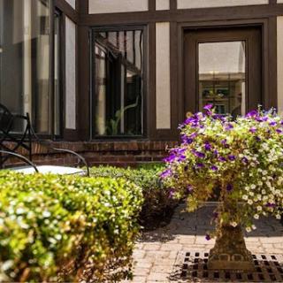 A vibrant courtyard featuring a flower arrangement, surrounded by well-maintained greenery and elegant architecture.