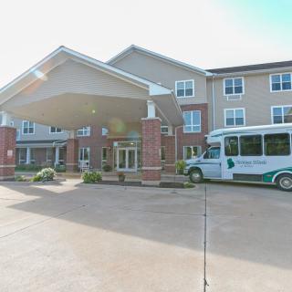 A retirement home's entrance with a shuttle bus parked outside.