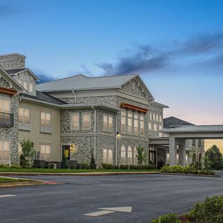 A modern residential building with a stone facade and well-maintained landscaping.