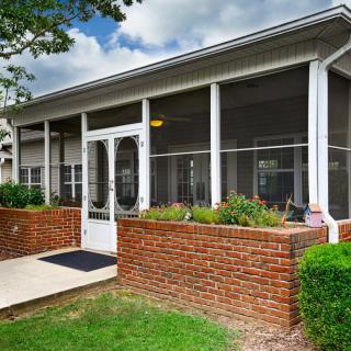 Screened porch with brick wall and entrance.