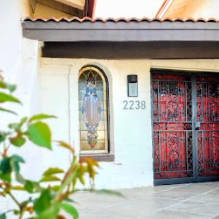 A welcoming entryway featuring decorative iron doors and a neatly landscaped front.