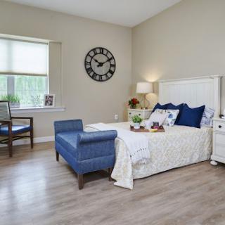 A serene and stylish bedroom featuring a blue and white color scheme, complemented by natural light and modern furnishings.