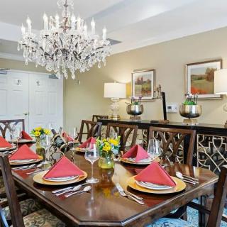 A beautifully set dining room with a chandelier and elegant table settings.