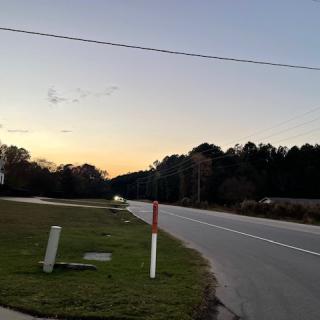 A quiet road at sunset with trees lining the horizon.
