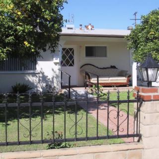 A small house with a front yard and bench under a sunny sky.