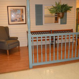A cozy seating area featuring a blue fence, a bench, an armchair, and decorative plants.