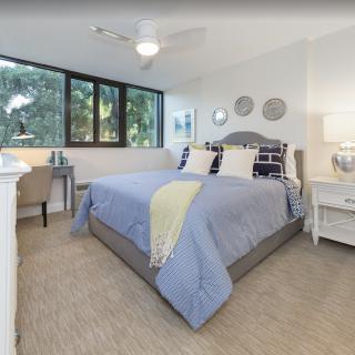 A cozy bedroom with stylish decor and a large window providing natural light.