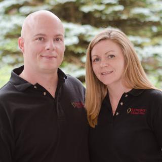 A couple posing together outdoors with trees in the background.