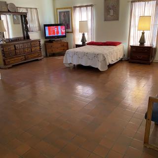 A spacious bedroom with a bed, television, and wooden furniture.