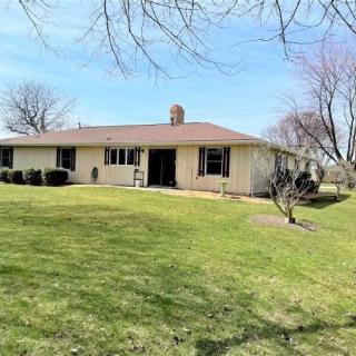 A ranch-style house with a spacious lawn and surrounding trees in a suburban area.