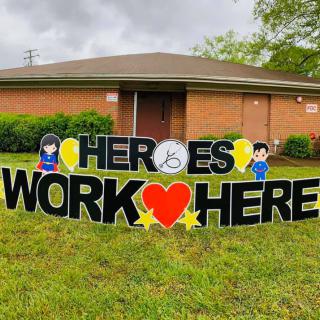 A lawn sign with the message 'Heroes Work Here' placed in front of a building.