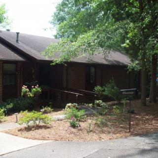 A wooden house surrounded by a garden with trees.