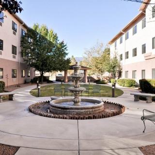 A tranquil courtyard featuring a central fountain surrounded by buildings and lush greenery.