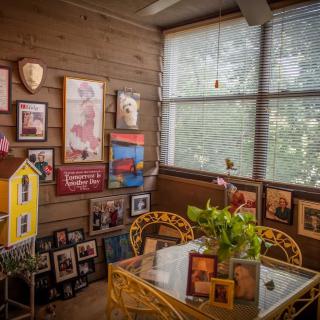 A cozy sunroom adorned with family photographs and artwork, complete with a table set for relaxation and indoor plants.