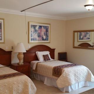 A cozy hotel room with two twin beds, decorated with framed art and a bedside lamp.