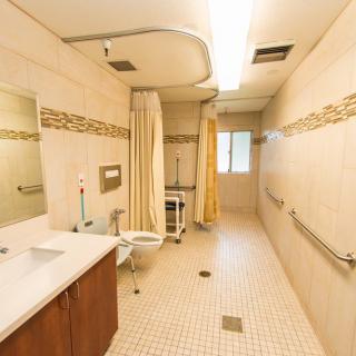 A spacious and accessible bathroom with a shower, sink, and grab bars.