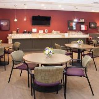 A cozy dining area with round tables, chairs, and a decorative arrangement on each table.
