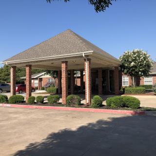 A welcoming entrance to a commercial building with a covered area and well-maintained landscaping.