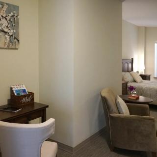 A cozy hotel room featuring a comfortable seating area, a work desk, and a neatly made bed.