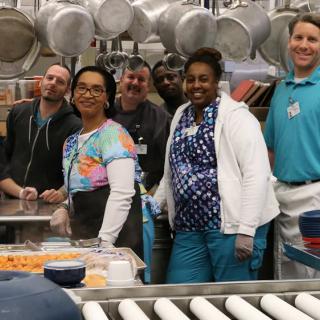 A group of people posing together in a kitchen setting.