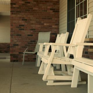 A serene outdoor setting featuring white wooden chairs on a porch.