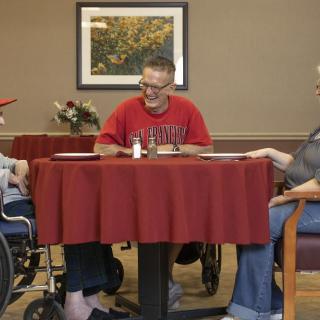 Three people sitting around a table having a conversation indoors.