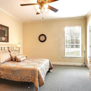 A cozy bedroom with neutral tones, featuring a bed and ceiling fan.