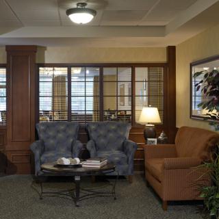 A cozy living room setup with a sofa, armchair, and coffee table, softly lit by a lamp.