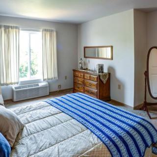 A cozy bedroom with a bed, dresser, and mirror, illuminated by natural light from the window.