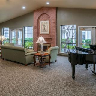 A cozy living room featuring a grand piano, comfortable couches, and a warm fireplace.