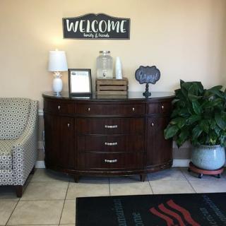 A welcoming lobby area with a wooden dresser, decor items, and a potted plant.