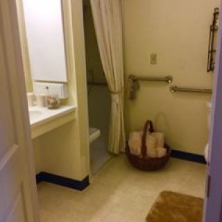A clean bathroom with a shower, sink, and towel basket.