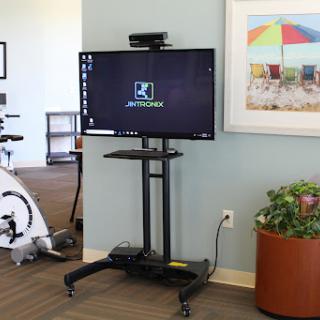 A mounted television on a mobile stand, set up in an exercise area.