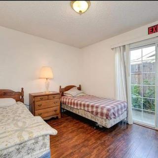 A simple bedroom with two beds, a nightstand, and a sliding glass door.