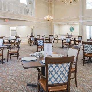 An elegant and spacious dining room with neatly arranged tables and chairs under a chandelier.