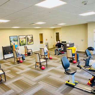 A rehabilitation facility with chairs and fitness equipment prepared for a group exercise session.