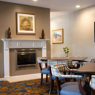 A cozy dining area with tables, chairs, and a fireplace adorned with artwork.