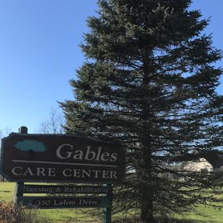 The Gables Care Center sign displayed against a backdrop of a tall tree and clear blue sky.
