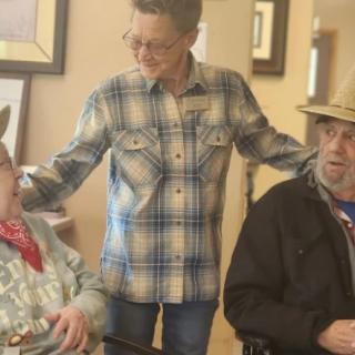 A supportive interaction between three people, two of whom are sitting in wheelchairs, indoors.