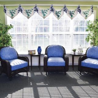 A cozy living room setup with three blue upholstered chairs, plants, and a large window letting in sunlight.