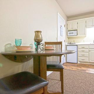 A cozy dining area adjacent to a compact kitchen, featuring modern decor and wooden furniture.