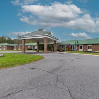 A welcoming entrance to a residential facility surrounded by greenery and blue skies.