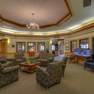 A cozy lobby area featuring a central seating arrangement with comfortable chairs, a chandelier, and a fish tank for ambiance.