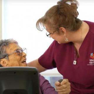 A nurse interacts warmly with an elderly patient, sharing a smile.