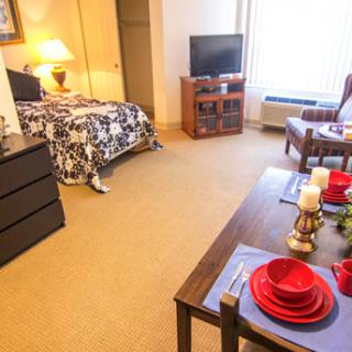 A cozy hotel room featuring a bed, TV, and a dining area set up for guests.