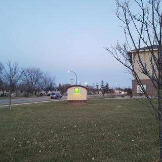 A peaceful evening scene featuring a building, a grassy area, and a tree.