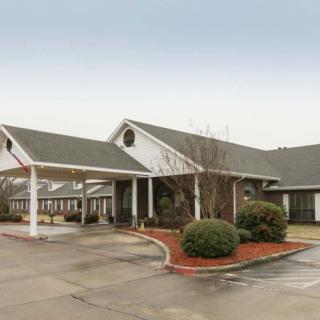 A single-story building with a covered entrance and landscaped surroundings.