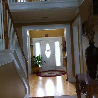 A welcoming home foyer with a staircase and a front door, adorned with plants and decorative items.