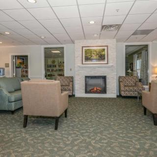 A cozy living room with armchairs, a fireplace, and a carpeted floor.