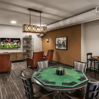 A stylish game room featuring a poker table, comfortable seating, and a television for entertainment.